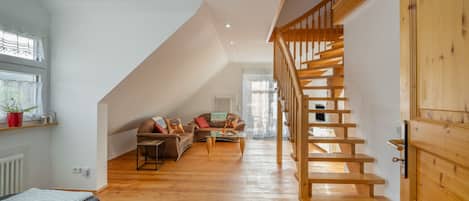 A modern interior with a wooden staircase, a sofa set, and a dining table.