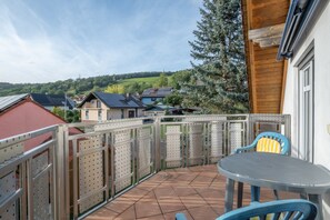 A patio with a table and chairs, a metal fence, and houses in the background.