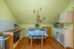 Cocina compacta con comedor, piso de madera y techo decorado con motivos florales.