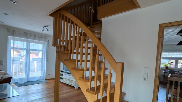 Una escalera de madera con diseño moderno que conduce a un piso superior.