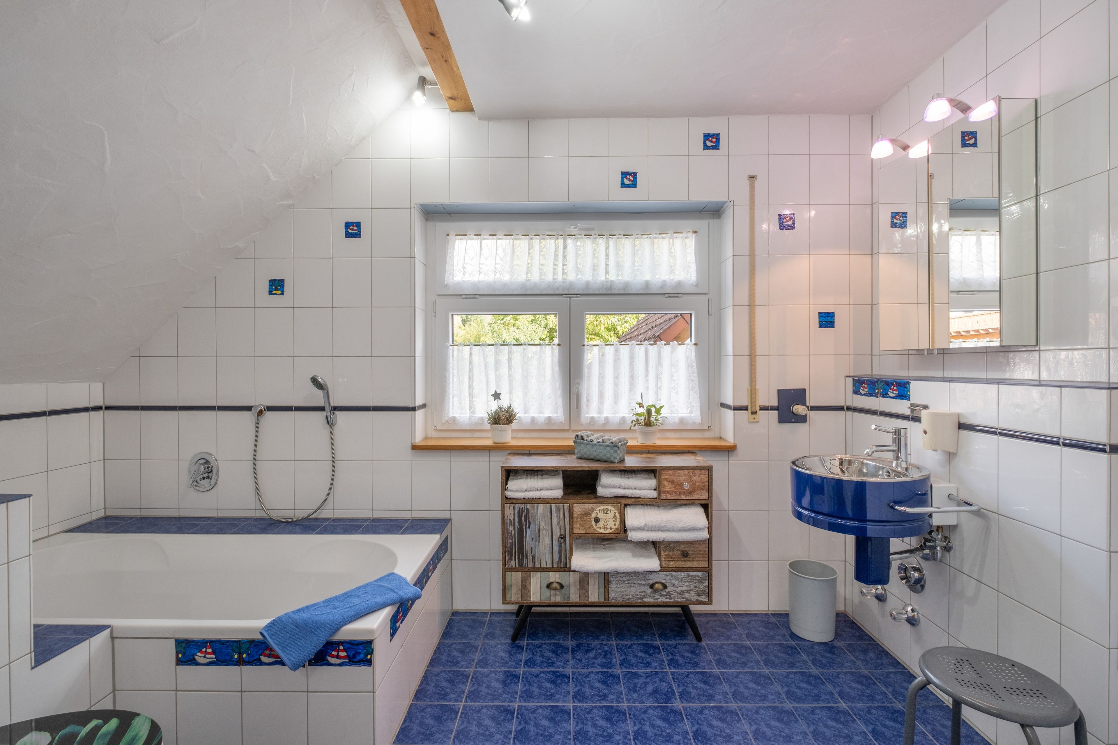 A bathroom with a bathtub, a sink, and a window with curtains.