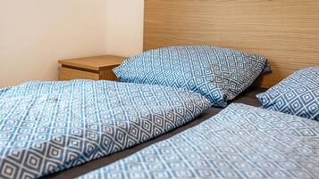 Una cama con colcha y almohadas de estampado geométrico, cabecera de madera y mesita de noche.