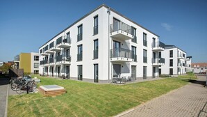 A modern apartment building with balconies, a paved driveway, and bicycles parked outside. - Terrace Loft by the Botanical Garden (Greifswald)