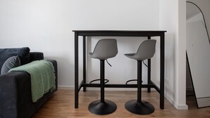 A room with a dark-colored sofa, two grey chairs, a small black table, and a white wall. - Terrace Loft by the Botanical Garden (Greifswald)