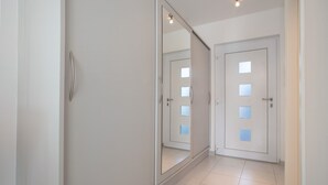 A hallway with a sliding door, a mirror, and a door with frosted glass panels. - Apartment 'Top Location with Cathedral View' with Wi-Fi (Greifswald)