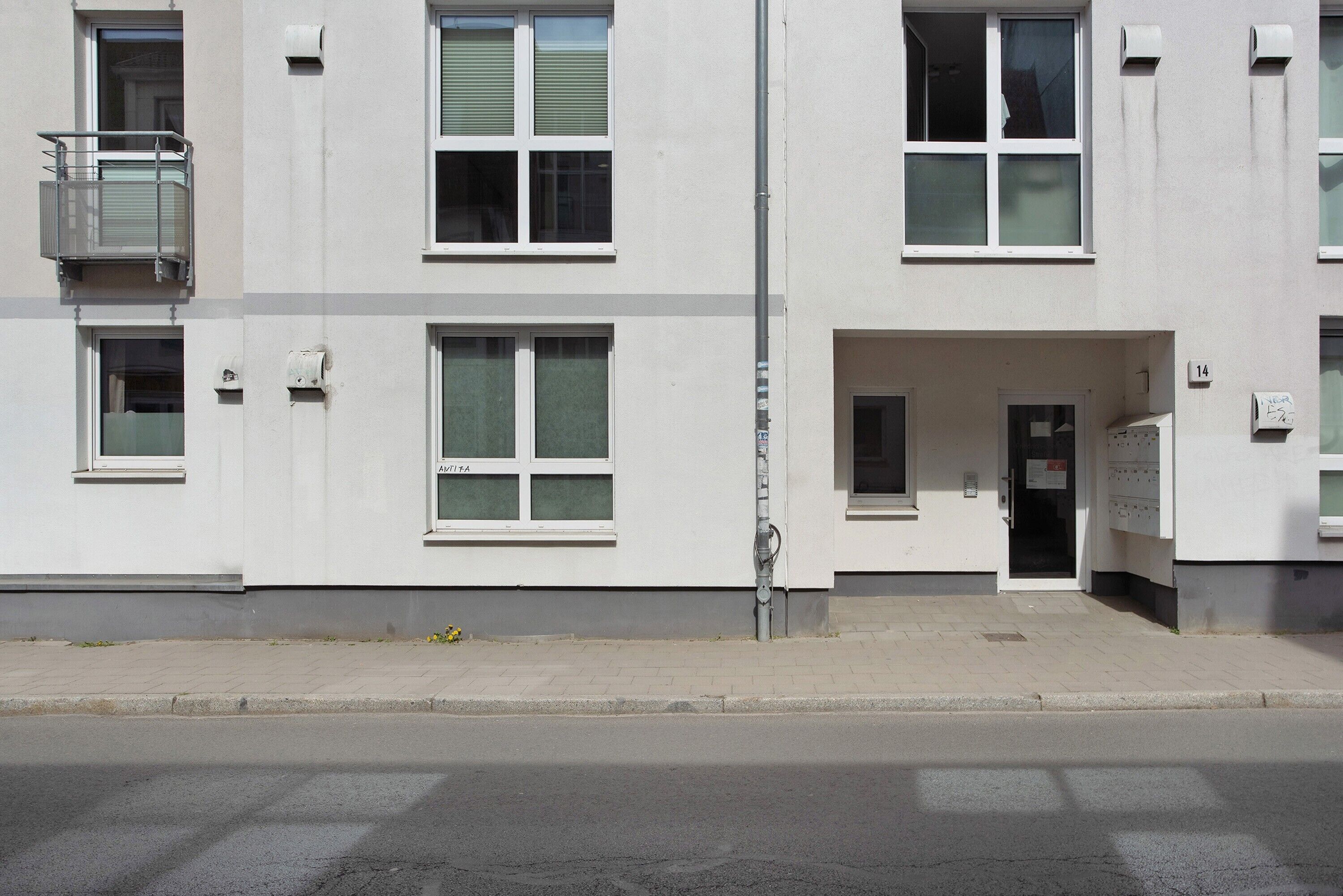 A multi-story building with a flat facade, large windows, and a visible entrance with a door.
