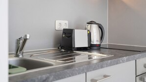 A kitchen with a modern design, featuring a stainless steel sink, a kettle, and a coffee maker. - Apartment 'Top Location with Cathedral View' with Wi-Fi (Greifswald)