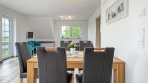 Een eethoek met een houten tafel, zwarte stoelen en een bloevas.