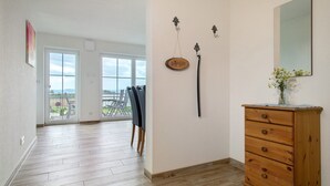 Een kamer met een houten dressoir, een spiegel en een kapstok met een jas.
