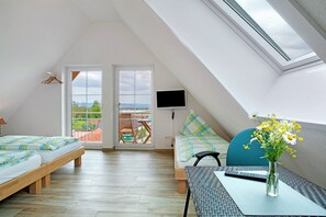 Une chambre avec un puits de lumière, une télévision, un lit, un bureau et un vase de fleurs.