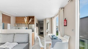 Ein modernes Interieur mit grauem Sofa, weißem Esstisch und Küchenbereich.