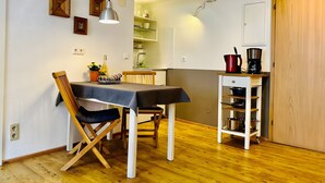 Un coin repas avec une table, des chaises, une machine à café et une cuisine en arrière-plan.