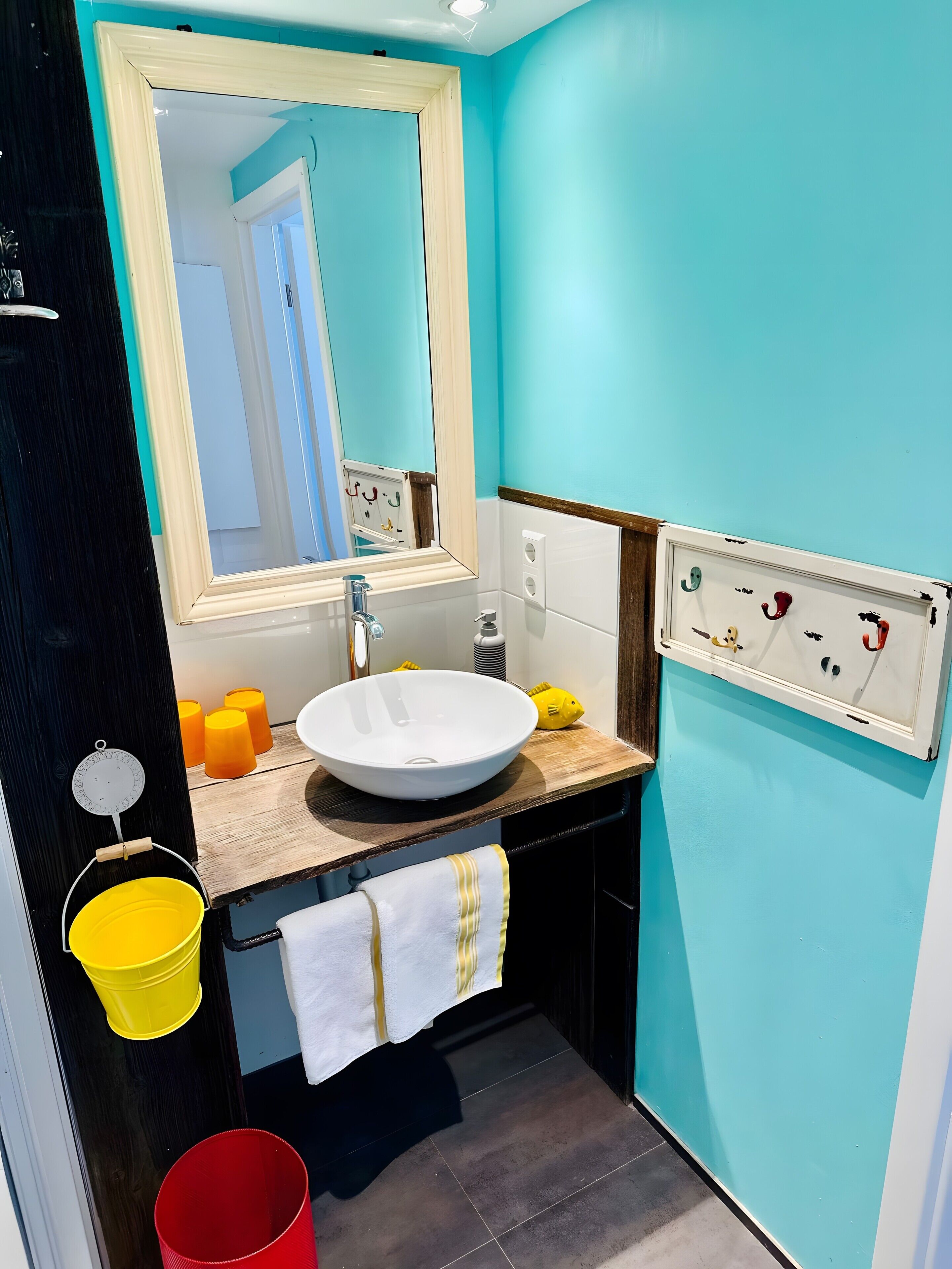 A bathroom with a white sink, a mirror, a towel, and a wall-mounted soap dispenser.
