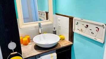A bathroom with a white sink, a mirror, a towel, and a wall-mounted soap dispenser.