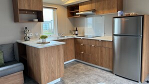 A modern kitchen with wooden cabinets, a stainless steel refrigerator, and a built-in island with a sink.