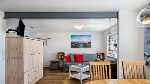 Een moderne woonkamer met een bank, een eettafel en een houten kast.