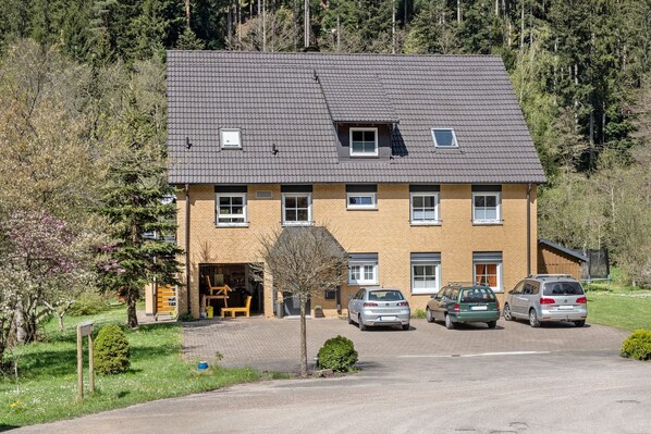 En tvåvåningsbyggnad med ett tak täckt av takpannor, ett garage och en uppfart där bilar står parkerade.