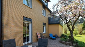 Een terras met een tafel en stoelen, een bakstenen muur en een boom met roze bloemen.