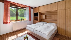 Ein Schlafzimmer mit einem Bett, Holzschränken, einem Fenster mit Vorhängen und einer Heizung.