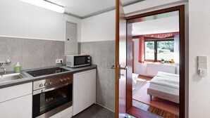 Eine kleine Küche mit Mikrowelle, Herd und Backofen, die in ein Schlafzimmer mit Bett und Fenster übergeht.
