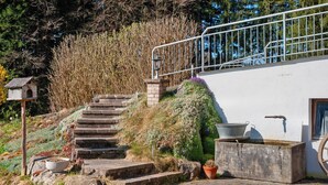 A staircase leading to a white building with a metal railing, a birdhouse, and potted plants. - Apartment 'Moos' with Private Terrace and Wi-Fi (Argenbühl)