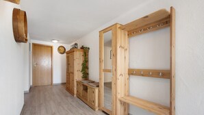 A hallway with wooden flooring, a coat rack, a bench, and a door. - Apartment 'Moos' with Private Terrace and Wi-Fi (Argenbühl)