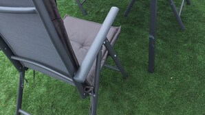 Une terrasse avec une table et des chaises, un pot de fleurs et, au fond, un bâtiment avec un toit recouvert de tuiles.