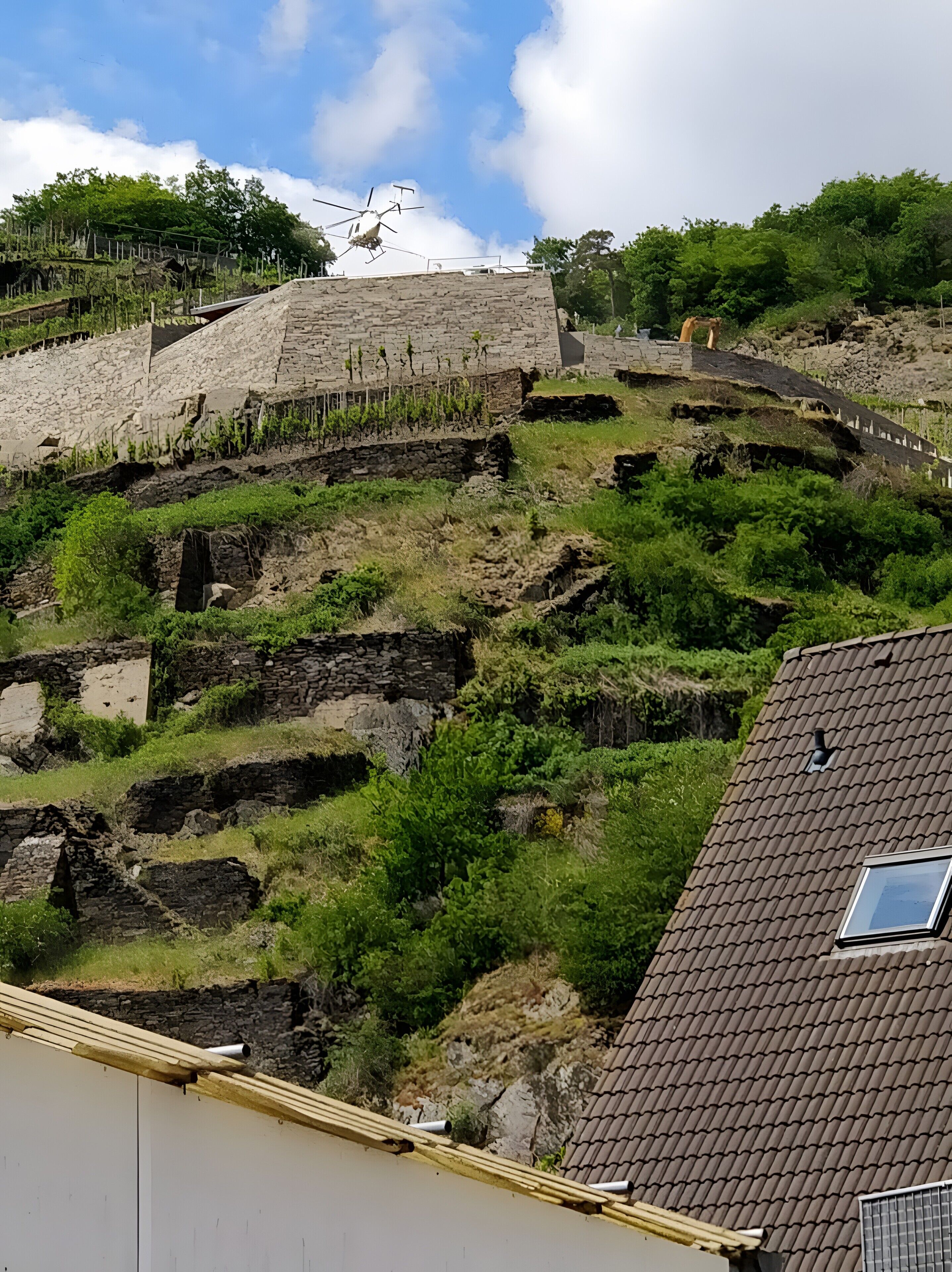 Een stenen gebouw met een trap, omgeven door groen en een heldere lucht.