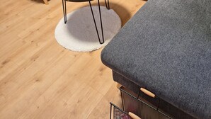Un salon moderne avec un canapé d’angle gris, une table basse ronde en bois et un tapis blanc.