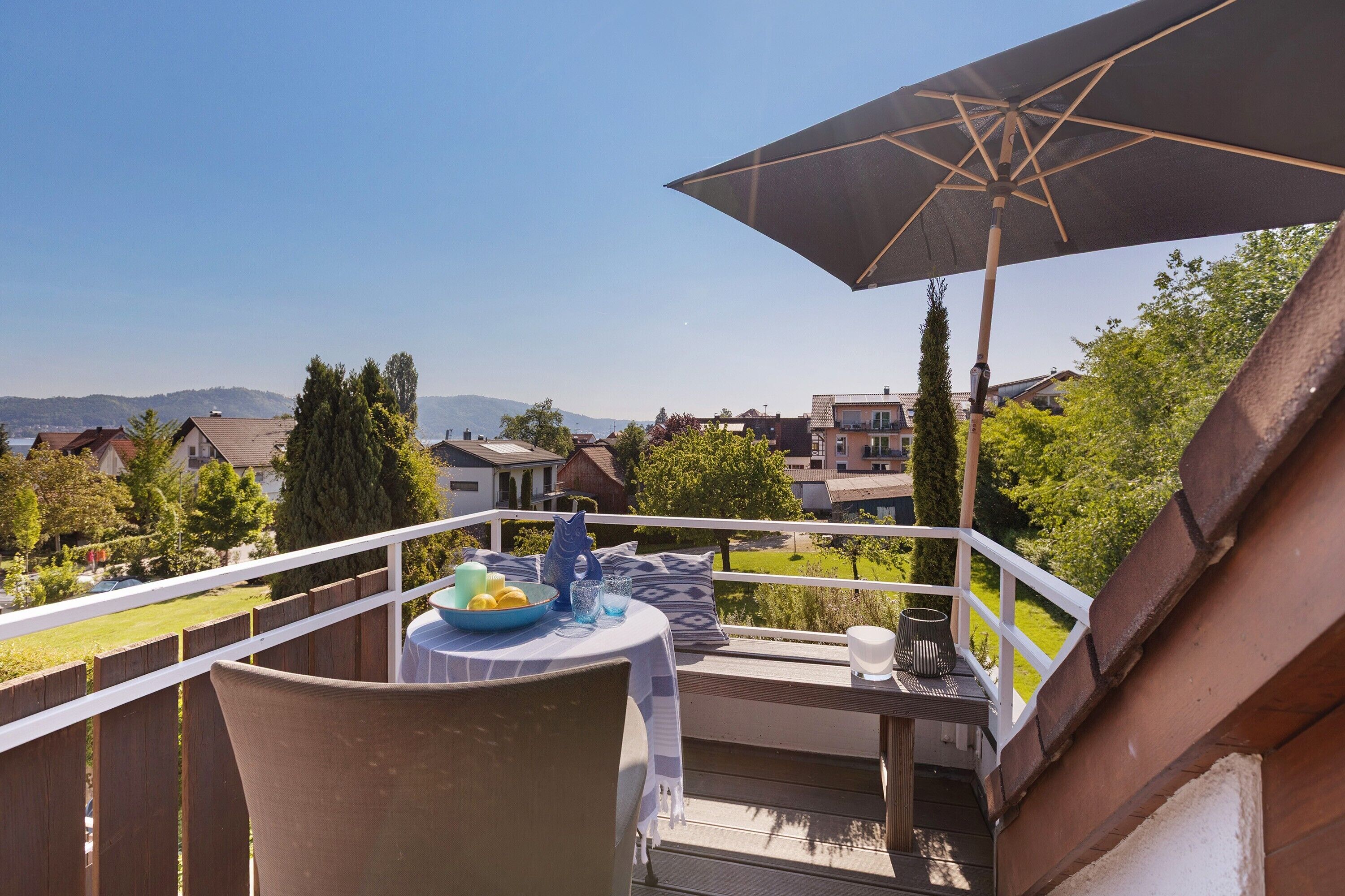 A balcony with a table, chairs, and an umbrella.