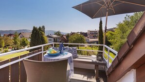 A balcony with a table, chairs, and an umbrella.