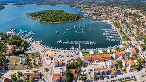An aerial view of a coastal town with a marina, residential buildings, and a small island. - Apartment near Pula with Sea View Balcony (Medulin)
