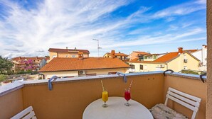A balcony with two drinks on a table, a white chair, and a view of buildings in the background. - Studio in Medulin near Bijeca Beach (Medulin)
