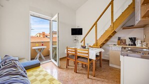 A compact living space with a dining area, kitchenette, and a balcony with a view of buildings. - Studio in Medulin near Bijeca Beach (Medulin)