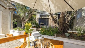 An outdoor seating area with a table set for two, featuring a coffee pot, glasses, and a tray.