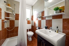 Une salle de bain avec douche, toilettes, lavabo et carrelage en marbre.