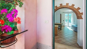 A room with a tiled floor, a wooden table, and a chair. There is a potted plant with flowers on the left side. - La Rocca by Interhome (Magione)