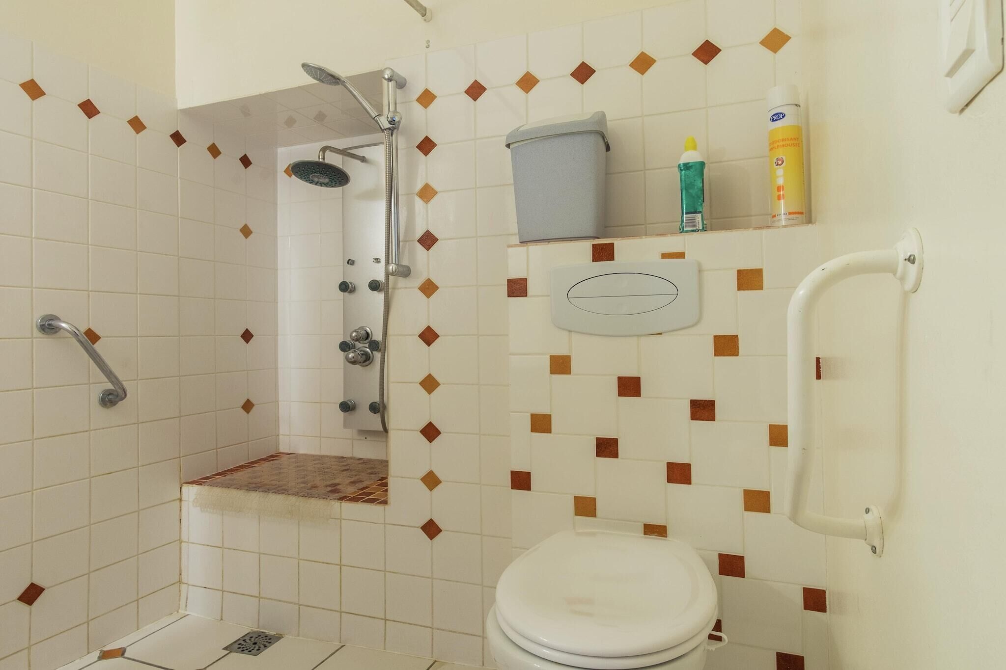 A bathroom with a shower, toilet, and a shelf with toiletries.