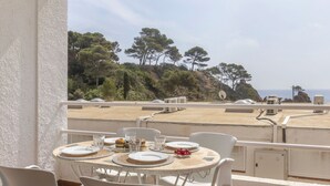 A terrace with a table set for dining, overlooking a scenic landscape with trees and a view of the sea. - AirMenuda by Interhome (Tossa de Mar)