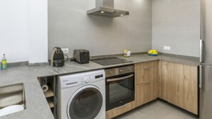 A modern kitchen with a built-in washing machine, a toaster, and a stove. - AirMenuda by Interhome (Tossa de Mar)