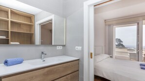 A modern bathroom with a wooden vanity, a large mirror, and a view of the sea through a sliding door. - AirMenuda by Interhome (Tossa de Mar)