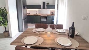 Eine moderne Küche mit dunklen Schränken, einem eingebauten Ofen und einem Essbereich mit einem Holztisch, gedeckt f ür vier Personen.