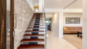 A modern staircase with a stone wall on one side and a glass railing. - Beautiful ocean views, beaches and bushwalks (MACMASTERS BEACH)