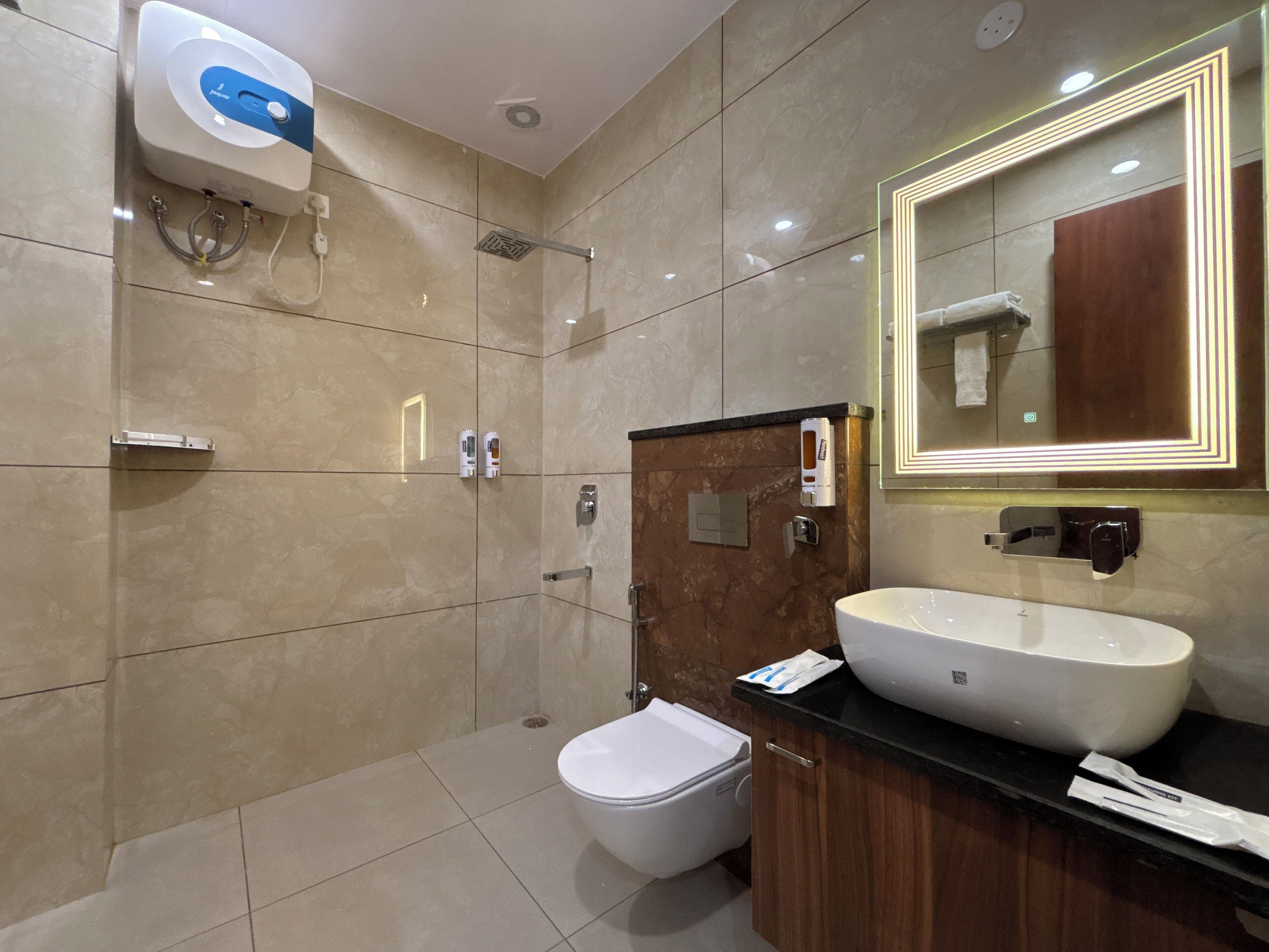 A modern bathroom with a large sink, a mirror with LED lighting, a shower, and a toilet.