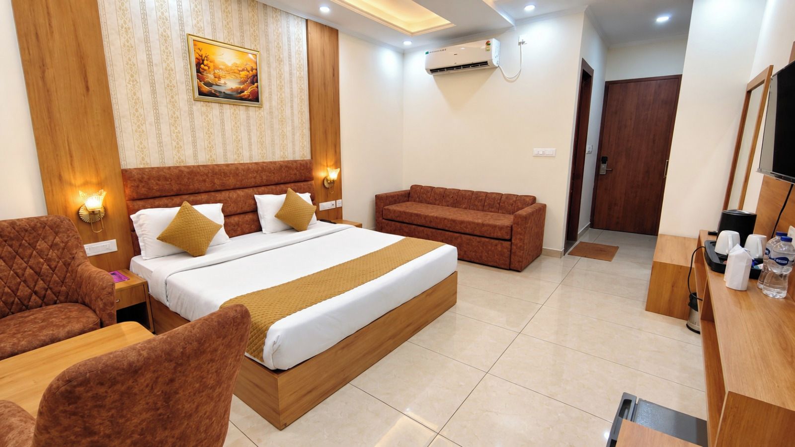 Una habitación de hotel con cama, sofá, escritorio y televisor.