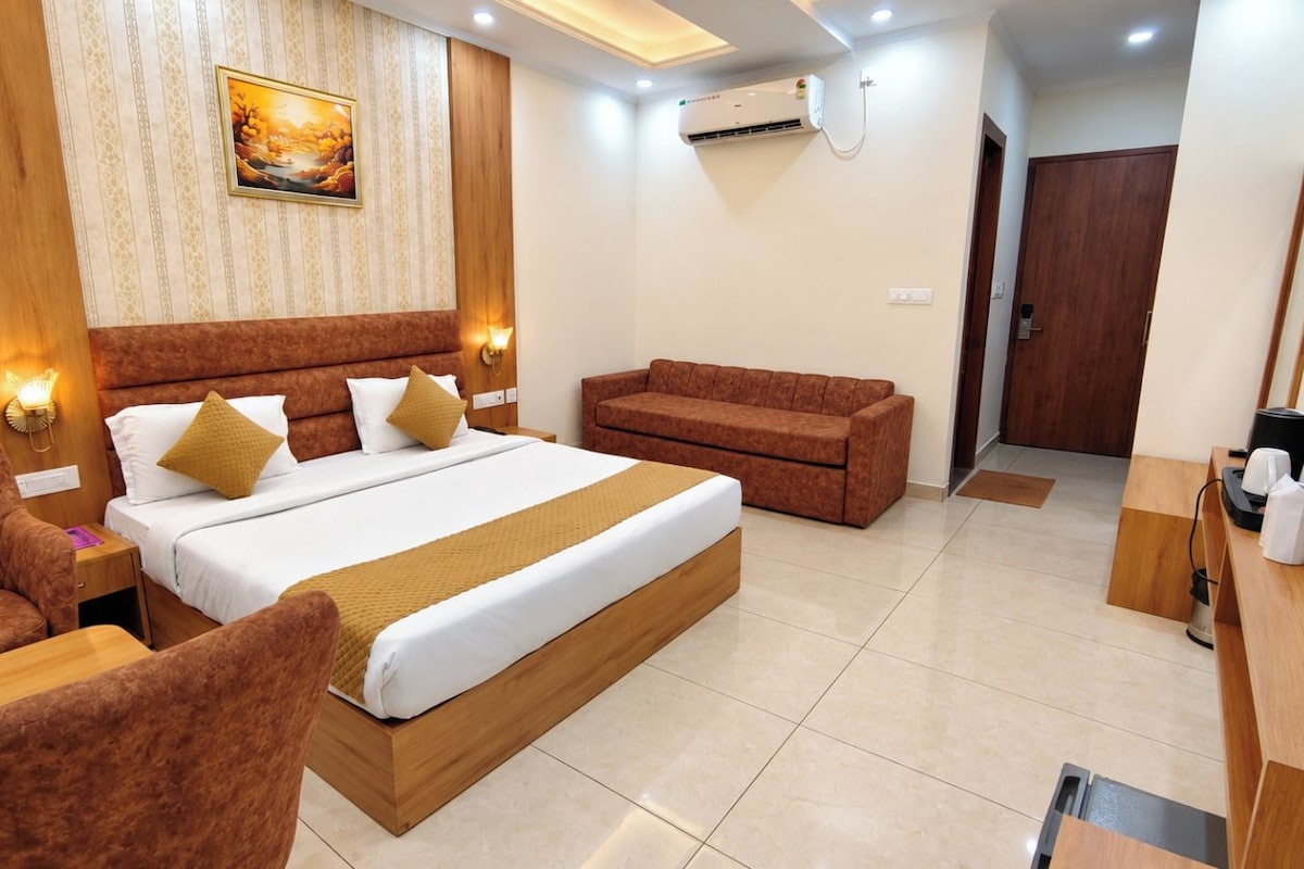 A hotel room with a bed, a sofa, a desk, and a TV.