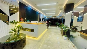 A modern reception area with a marble floor, a reception desk, and potted plants. - The Castle View (Haridwar)