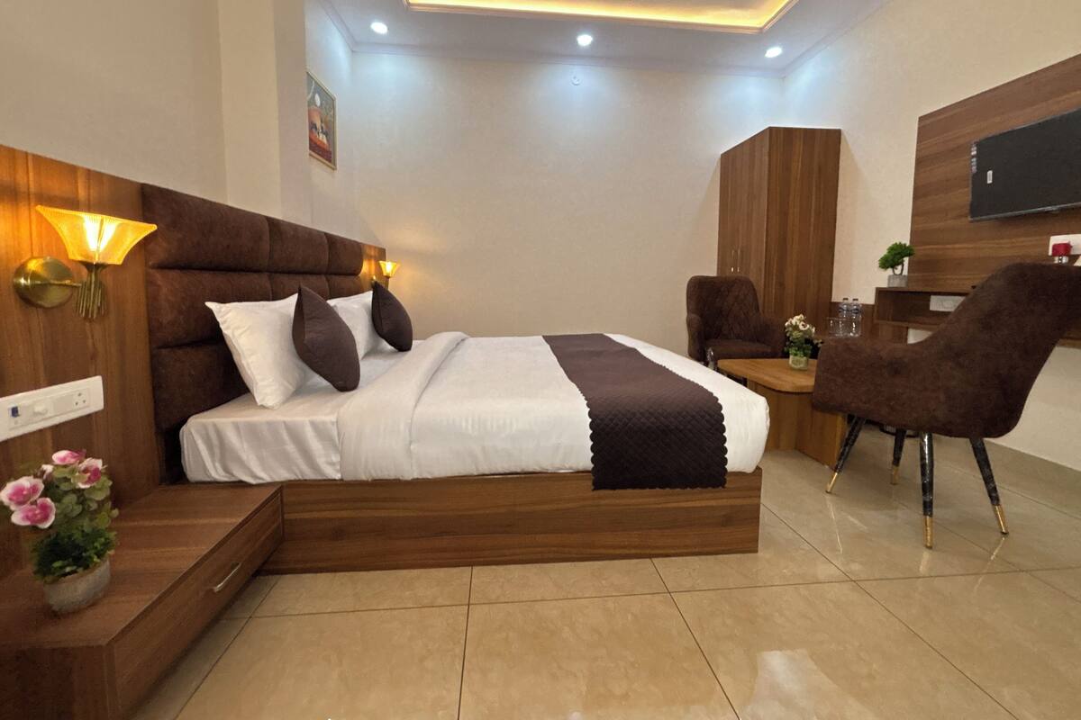 Une chambre d’hôtel moderne avec un grand lit, une tête de lit en bois, un bureau et une chaise.