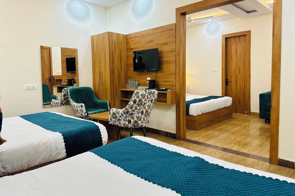 Une chambre d’hôtel avec deux lits, un bureau, une télévision et un miroir.