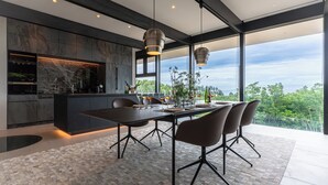 A modern kitchen with a large island, dark cabinetry, and a view of the outdoors. - KISIN (Yoichi)